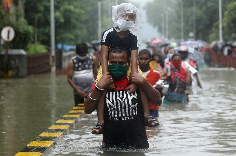A man carries a child through a waterlogged road after heavy rainfall in Mumbai, India. REUTERS/Francis Mascarenhas  